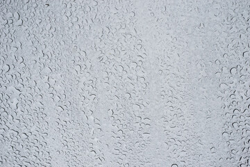 Closeup of rain drops on window on grey sky background