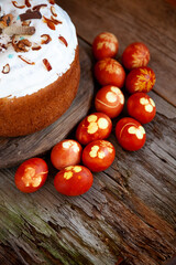 Easter cake and colored eggs. Rustic food on a wooden table. Egg colored with onion peel. Clover and dill leaves pattern. Classic food for the Easter holiday