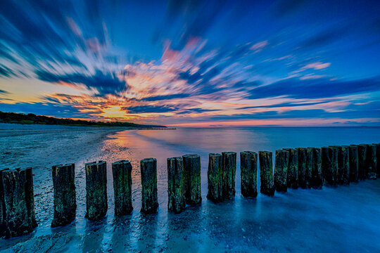 Sonnenuntergang Strand zur Blauen Stunde mit Bunen und verwischten Wolken