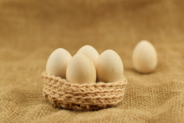 Decorative wooden Easter eggs in a wicker basket. Eastern eggs closeup on a vintage background.