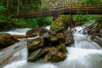 wooden bridge over a wild mountain creek with huge rocks