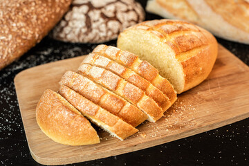 Sliced bread on the table on a background of various breads.