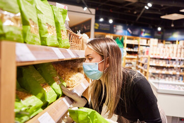 Woman as a customer with face mask when shopping for groceries