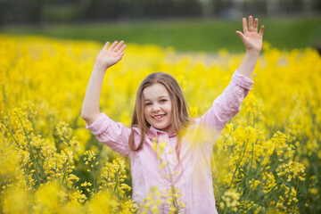 Naklejka na ściany i meble cheerful happy girl in a summer field with yellow rapeseed