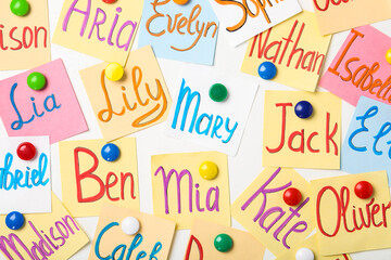 Colorful paper sheets with written different baby names on white background, flat lay