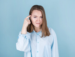 Portrait of young woman thinking with finger to head isolated on blue background