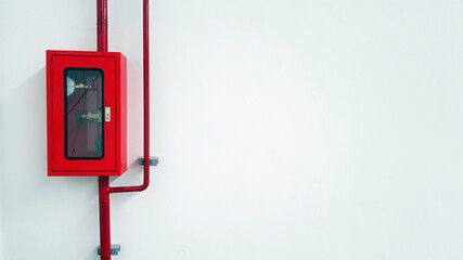 Red stainless steel box contain for water valve opener for fire fighting with water pipeline or pipe on white wall with copy space on right. Safety box and equipment for protection in case emergency c