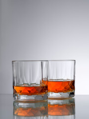 close up view of two glasses with ice and whiskey on grery background