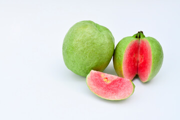One whole guava fruit, a half and a slice with pink flesh isolated on white background	
