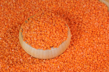 Red lentils in wooden container  top view.  Peeled lentil seeds. High protein product. The legume family. Healthy organic food diet concept. Marketing, advertising use. Studio shot.