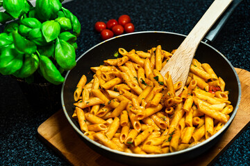 Penne pasta amatriciana in tomato sauce and cheese decorated with basil, top view.
