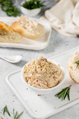 Chicken pate in a white bowl on a light gray kitchen table. Homemade chicken fillet pate with seasonings on a light background	
