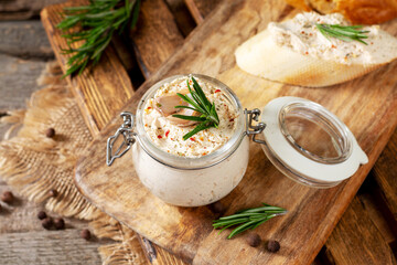 Chicken pate in a glass jar on the brown wooden kitchen table. Homemade chicken fillet pate with seasonings on a wooden background
