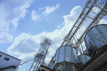 Fototapeta na wymiar Modern granaries for storing cereal grains against blue sky, low angle view