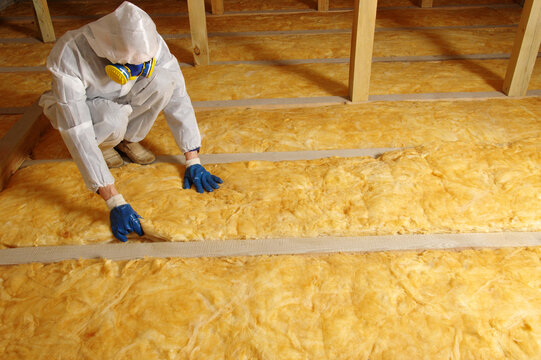 Man installing thermal insulation layer under the roof