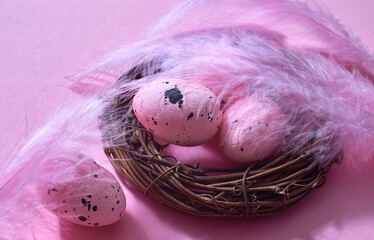 a nest with pink eggs and feathers. easter pink background