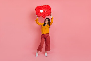 Full-length portrait of cheerful girl in culottes and yellow blouse holding like instagram sign