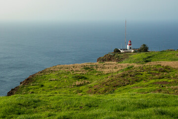 Lighthouse on the cliff with green grass around