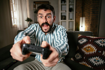 Fototapeta na wymiar Young attractive man playing video games in the living room. Handsome man having fun at home.