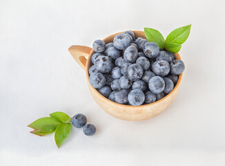 Fresh blueberries in a wooden bowl on a white background