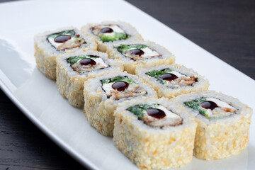 traditional Japanese sushi with eel, soft cheese and white sesame seeds, decorated with a drop of sauce. Japanese kitchen. Japanese restaurant. sushi on a white plate