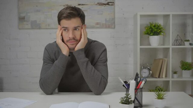 bored man puffing cheeks while sitting at workplace