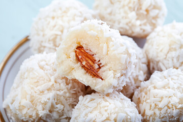 Coconut balls, raw and healthy sugar free rafaello candies. Vegetarian energy sweets recipe step by step. Round tasty dessert in ceramic bowl. Copy space, close up view. Healthy organic food for kids.