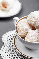 Plate with coconut candies on wooden table