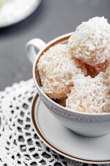 Homemade white chocolate and coconut sweets on a plate on the table. Snowball candy truffles. Selective focus