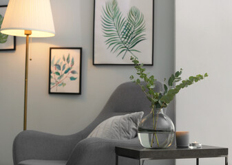 Vase with fresh eucalyptus branches on table in living room. Interior design