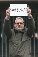 Angry and disgruntled mature man protesting with placard. Swearing and cursing. Outraged activist.