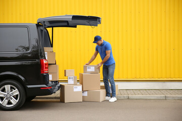 Courier with parcels near delivery van outdoors