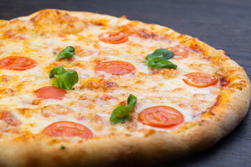 Delicious italian pizza with fresh tomatoes, olives and basil on old wooden board