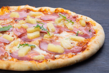 Delicious italian pizza with fresh tomatoes, pineapples, olives and basil on an old wooden board