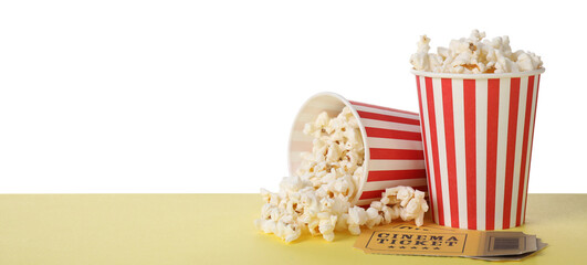Cups with delicious popcorn and tickets on table against white background