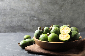 Delicious fresh feijoas on black table, space for text