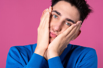 A young man gestures with his hands. Pink background. Consent and denial. Good and bad.