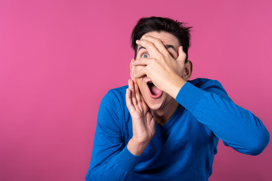 The young man is surprised. Pink background. Blue clothes.