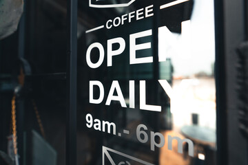 Fototapeta premium open sign attached to a glass in front of the coffee shop