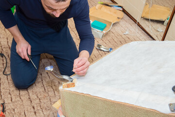 A man, a European, 40 years old, repairs furniture in his home.