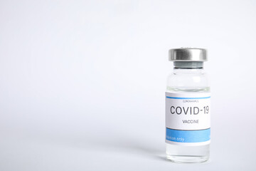 Vial with coronavirus vaccine on white background, space for text