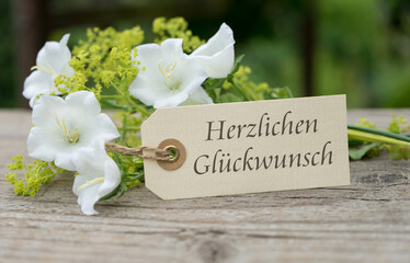 Greeting card with white bell flowers and german text  congratulations