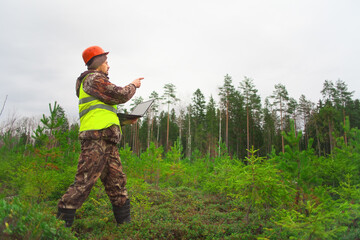 Forest ecologist works in the forest with a computer. Digital technologies in forestry. Computer forest inventory.