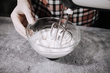 Cooking cream for cake in a glass bowl and mixer.