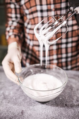 Cooking cream for cake in a glass bowl and mixer.