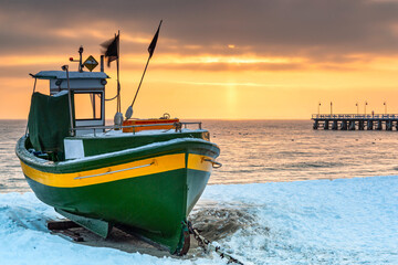 Obrazy na Szkle  Kuter rybacki na zaśnieżonej plaży w Gdyni Orłowie o wschodzie słońca, Morze Bałtyckie. Polska.