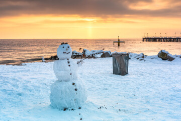 Snowman on the beach of the Baltic Sea in winter at sunrise, Gdynia Orłowo. Poland.