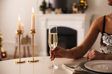 Woman with glass of champagne at table indoors, closeup