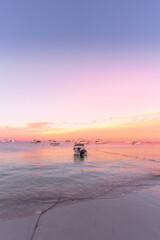 Romantic dawn pink beach with a floating boat