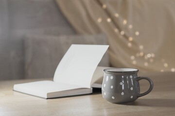 Cup of hot tea and book on the table, cozy home interior background